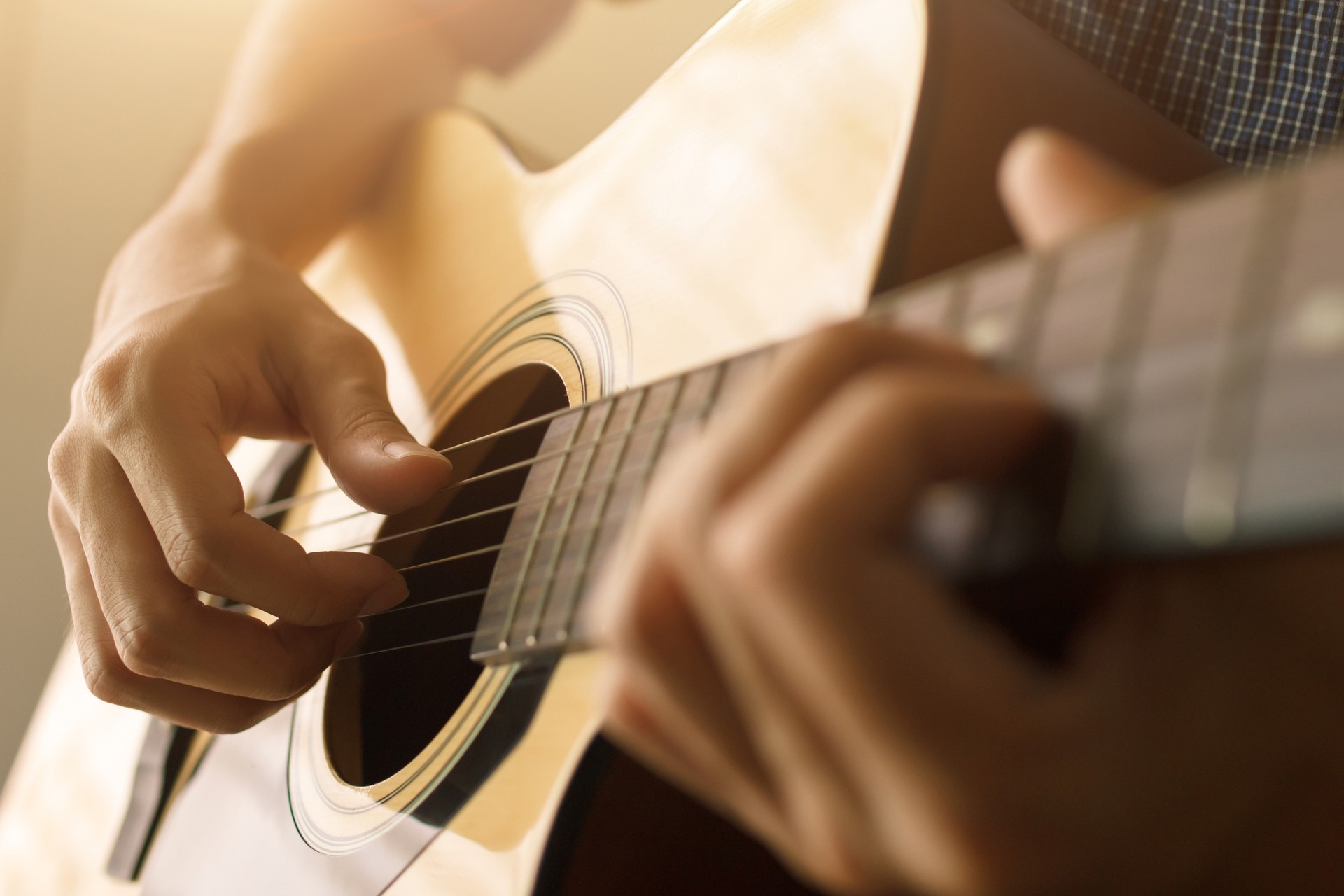 Man's hand playing acoustic guitar